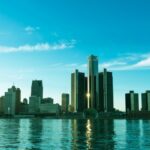 A beautiful view of the Detroit skyline reflecting on the river at sunrise, showcasing modern skyscrapers.