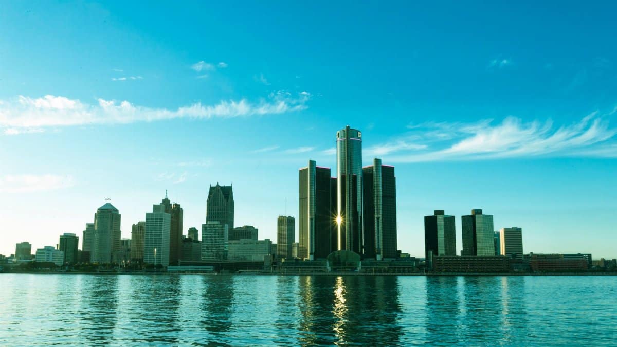 A beautiful view of the Detroit skyline reflecting on the river at sunrise, showcasing modern skyscrapers.