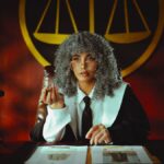 Portrait of a judge in a courtroom with the scales of justice emblem in the background.