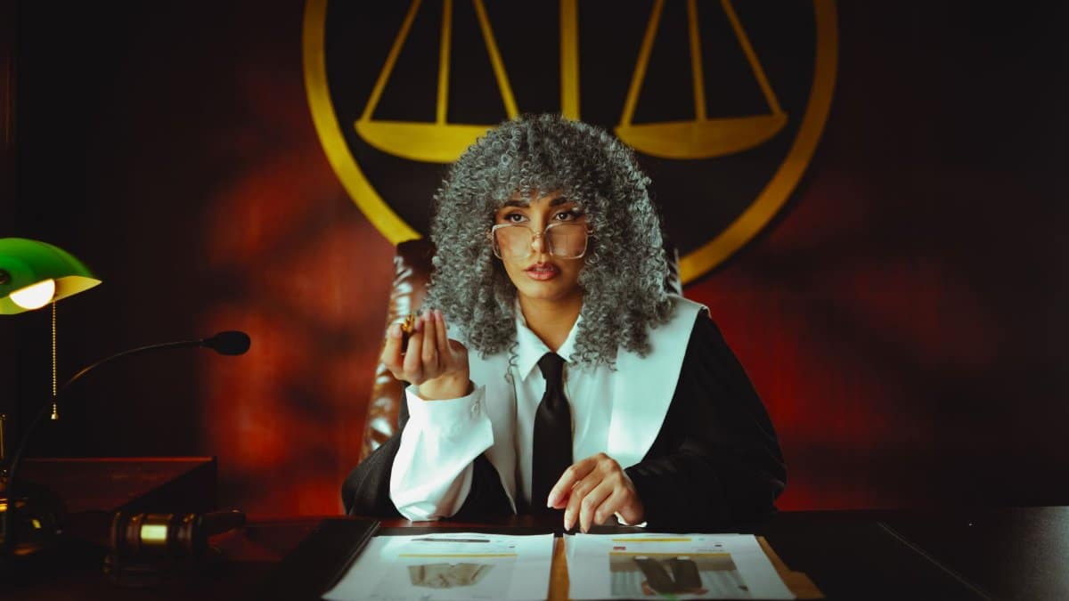 Portrait of a judge in a courtroom with the scales of justice emblem in the background.