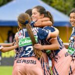 Teenage girls' soccer team celebrating a victory on the field outdoors.