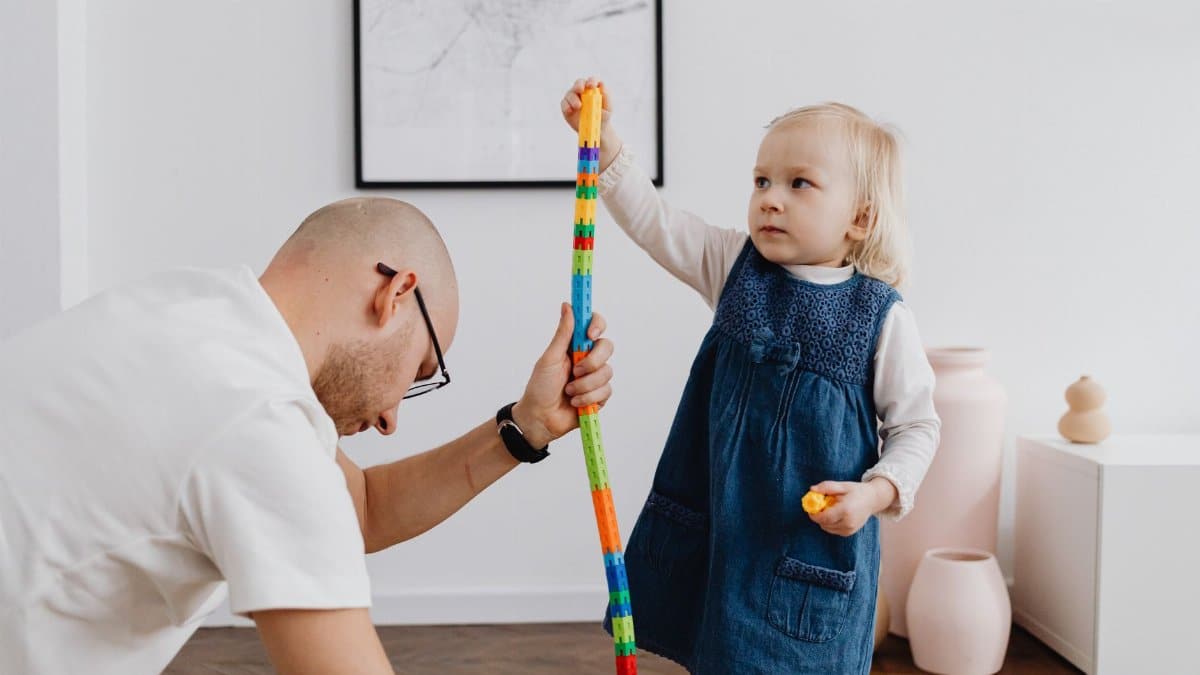 Father and daughter bonding through playtime activities, building a colorful block tower.