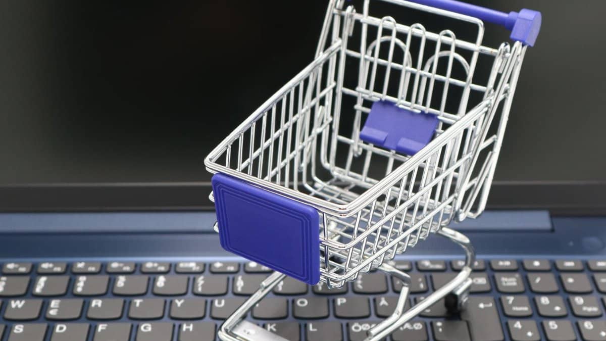 A mini shopping cart placed on a laptop keyboard, symbolizing online shopping and digital retail.