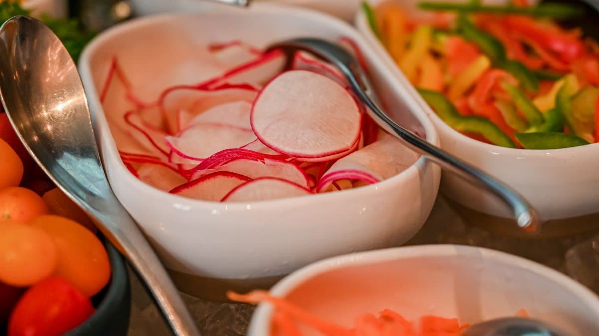 A vibrant display of fresh sliced vegetables in elegant white bowls, perfect for healthy dining.