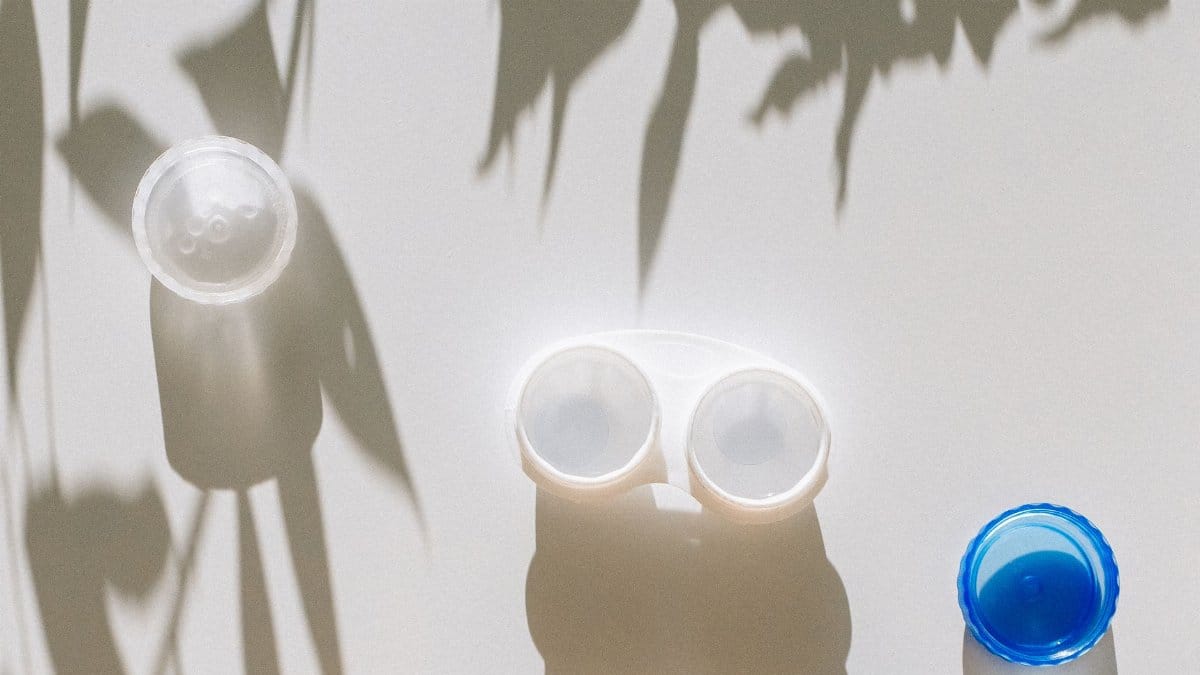 Top view of a contact lens case on a white table with shadow play, evoking simplicity and cleanliness.
