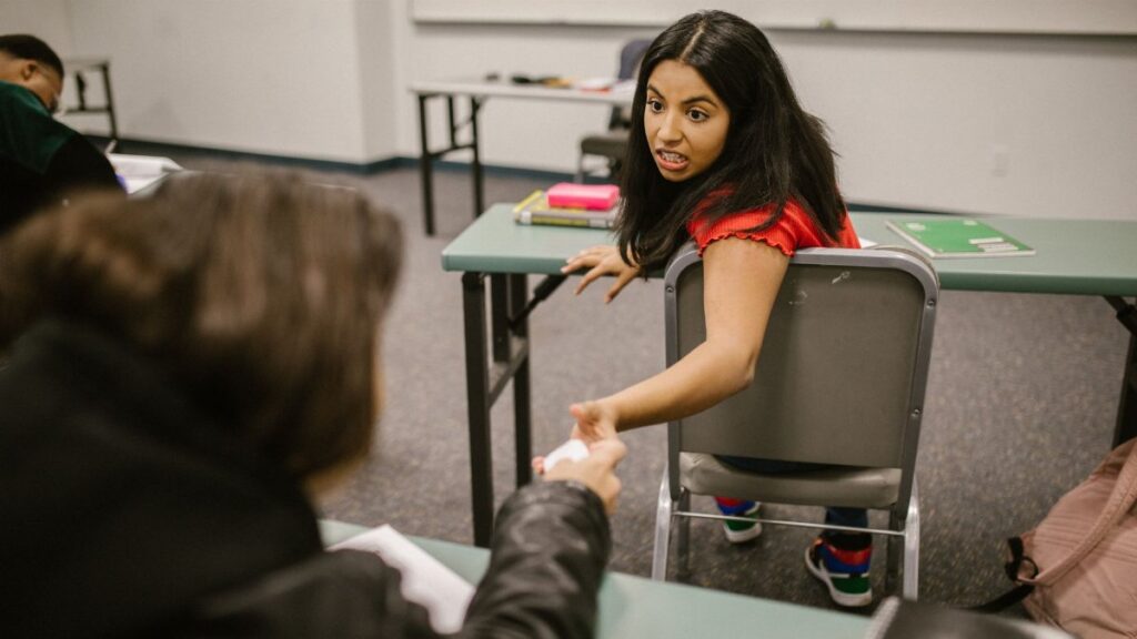 Students sharing notes during an indoor college class in a playful setting.