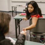 Students sharing notes during an indoor college class in a playful setting.