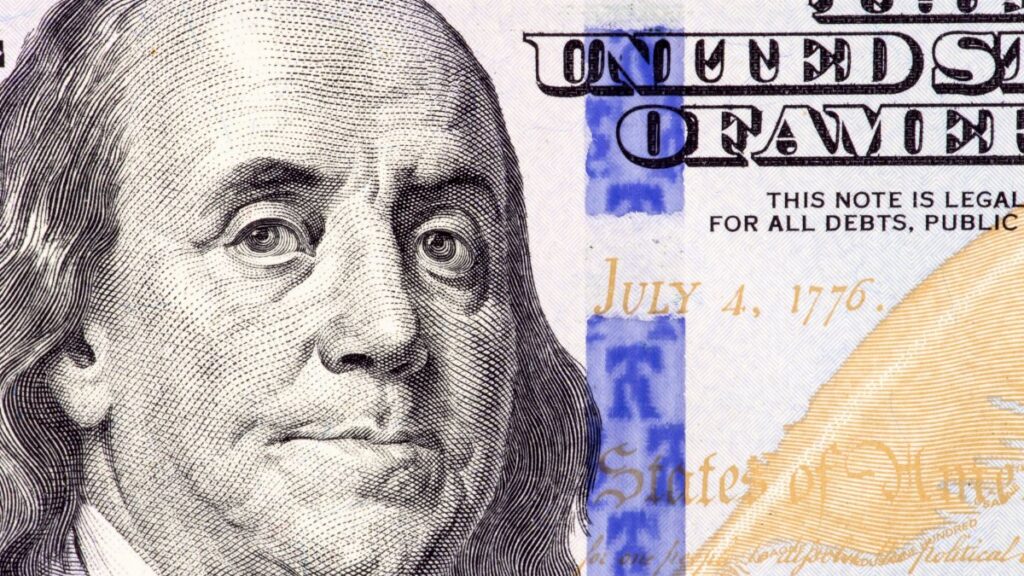 Detailed close-up of Benjamin Franklin's portrait on a 100 dollar bill showing July 4, 1776.