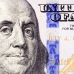 Detailed close-up of Benjamin Franklin's portrait on a 100 dollar bill showing July 4, 1776.