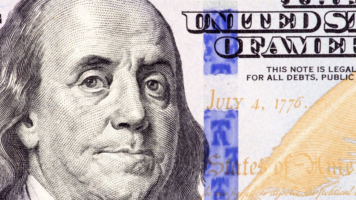 Detailed close-up of Benjamin Franklin's portrait on a 100 dollar bill showing July 4, 1776.