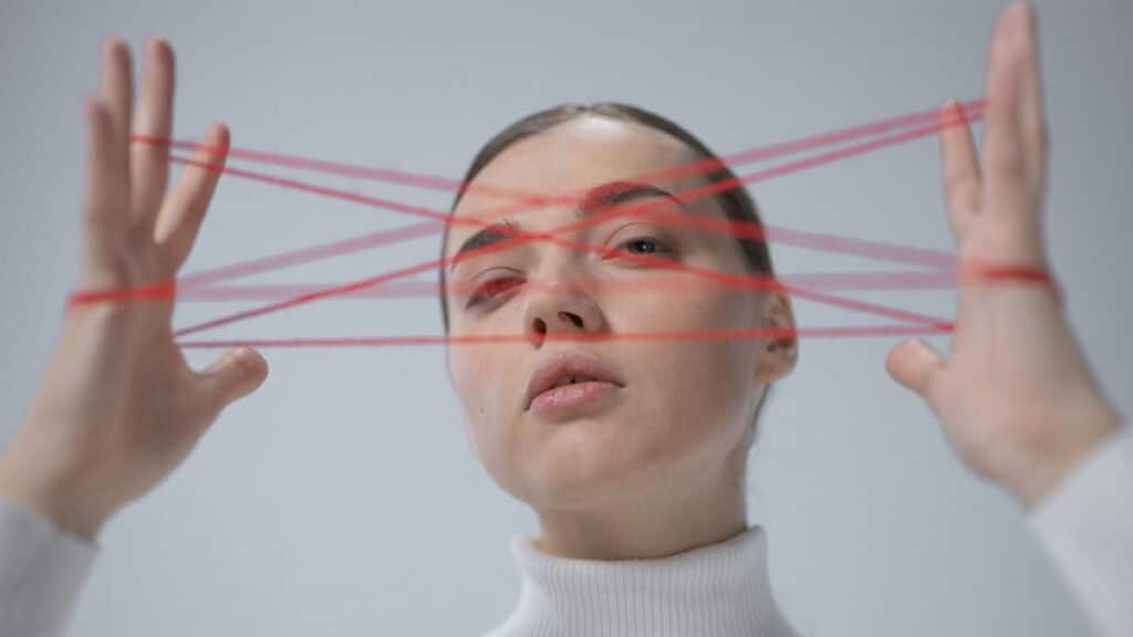 Creative portrait of a woman interacting with a red string art concept.