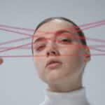 Creative portrait of a woman interacting with a red string art concept.