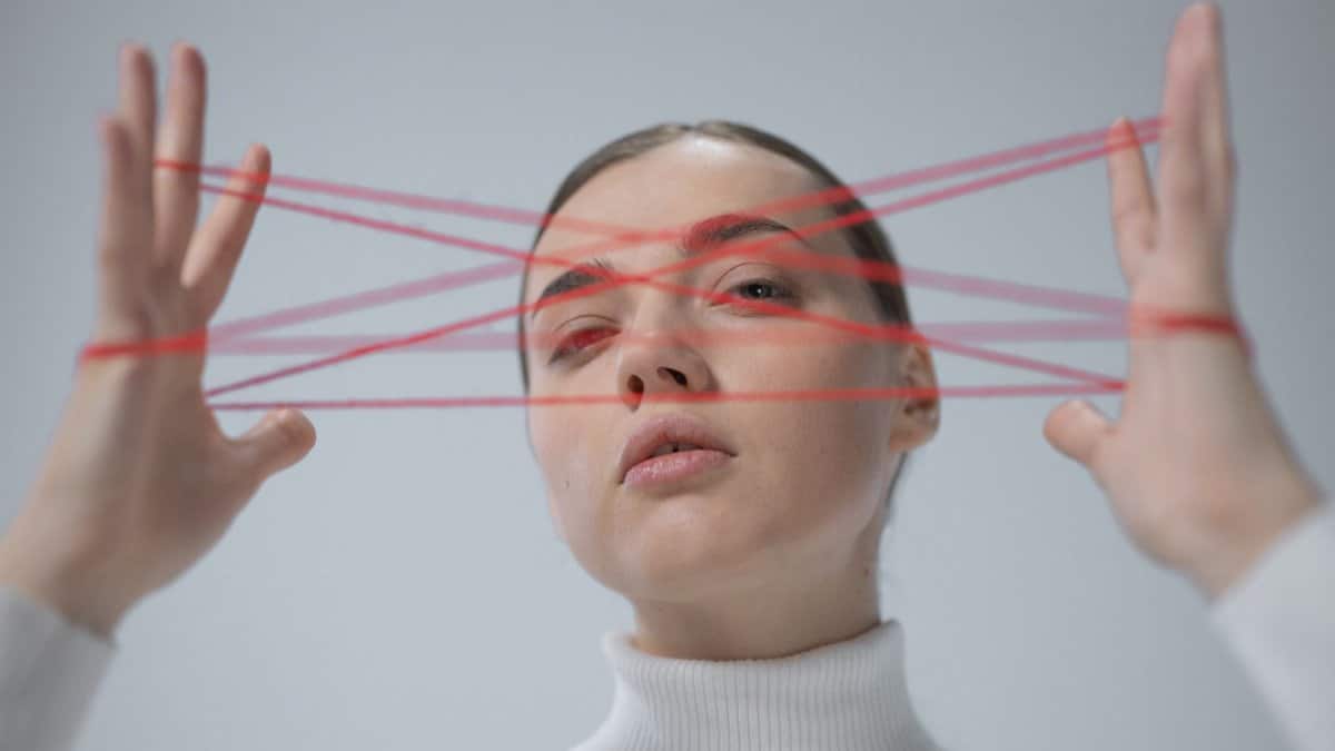 Creative portrait of a woman interacting with a red string art concept.