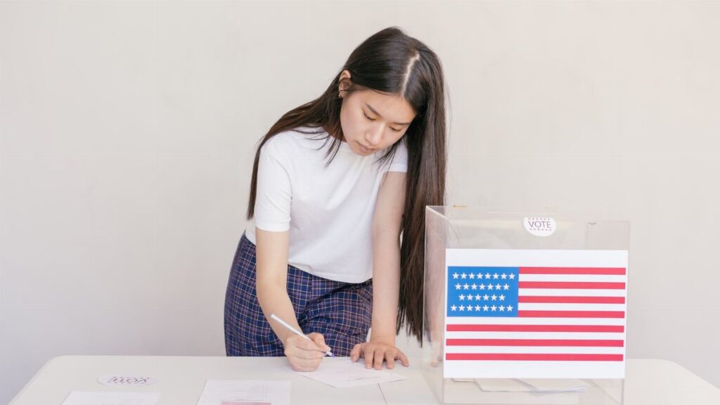 Woman voting in an election, writing down her choice at a ballot box with the American flag.