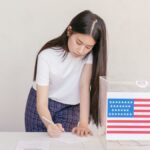 Woman voting in an election, writing down her choice at a ballot box with the American flag.