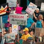 A diverse group of protesters holds signs advocating for freedom and democracy at a daytime rally.