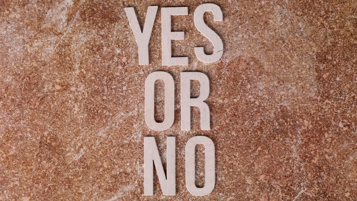 Wooden letters on marble background spell 'YES OR NO' symbolizing choices.