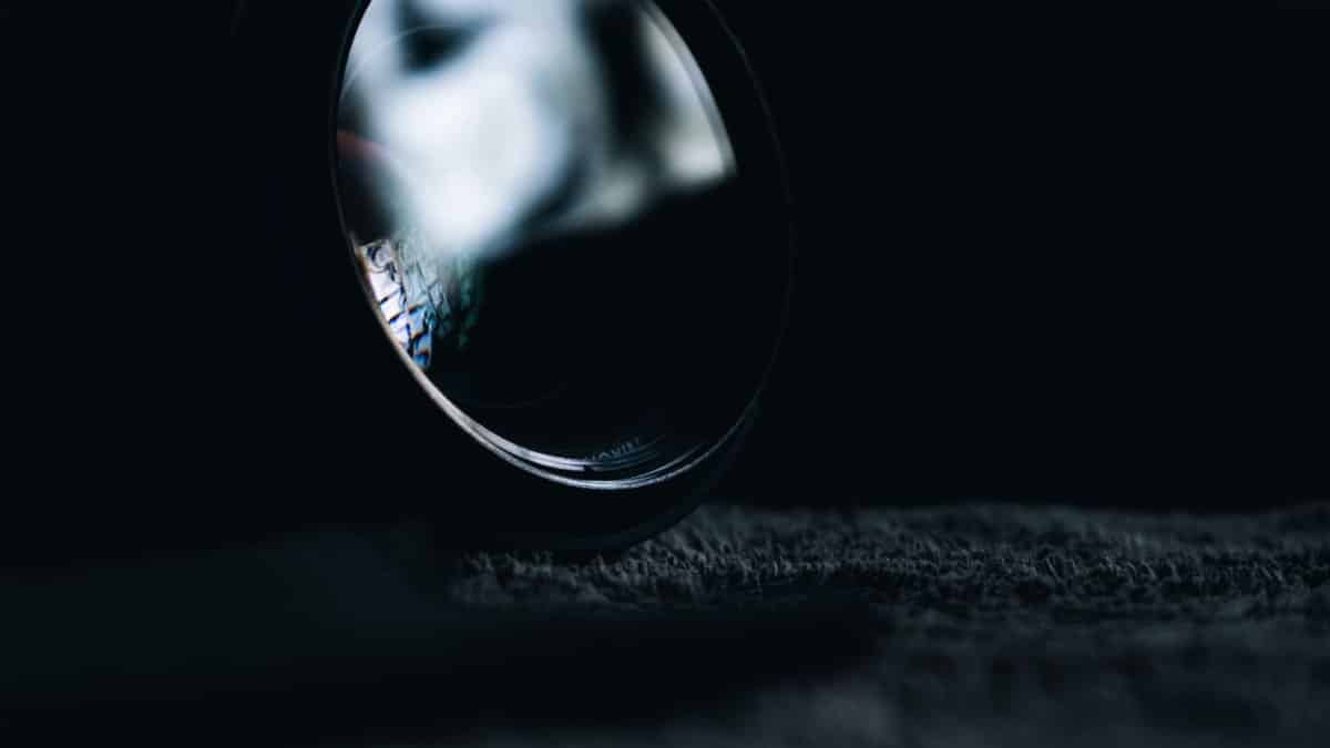 Moody close-up of a camera lens with artistic reflections on a textured surface.