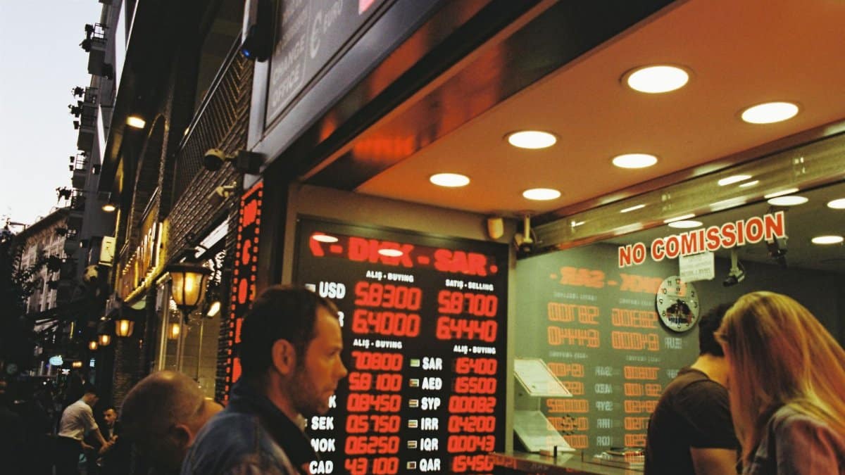 People gathering at a currency exchange office on a busy city street during dusk.