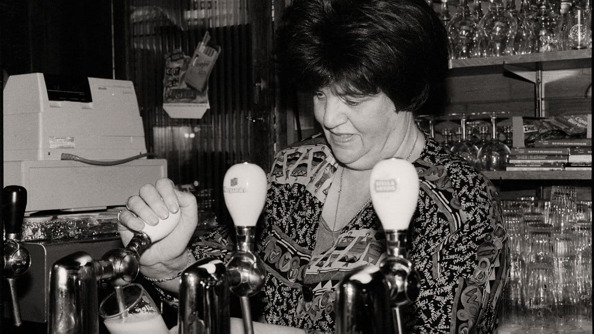 Black and white image of a bartender skillfully pouring draft beer at a vintage pub.