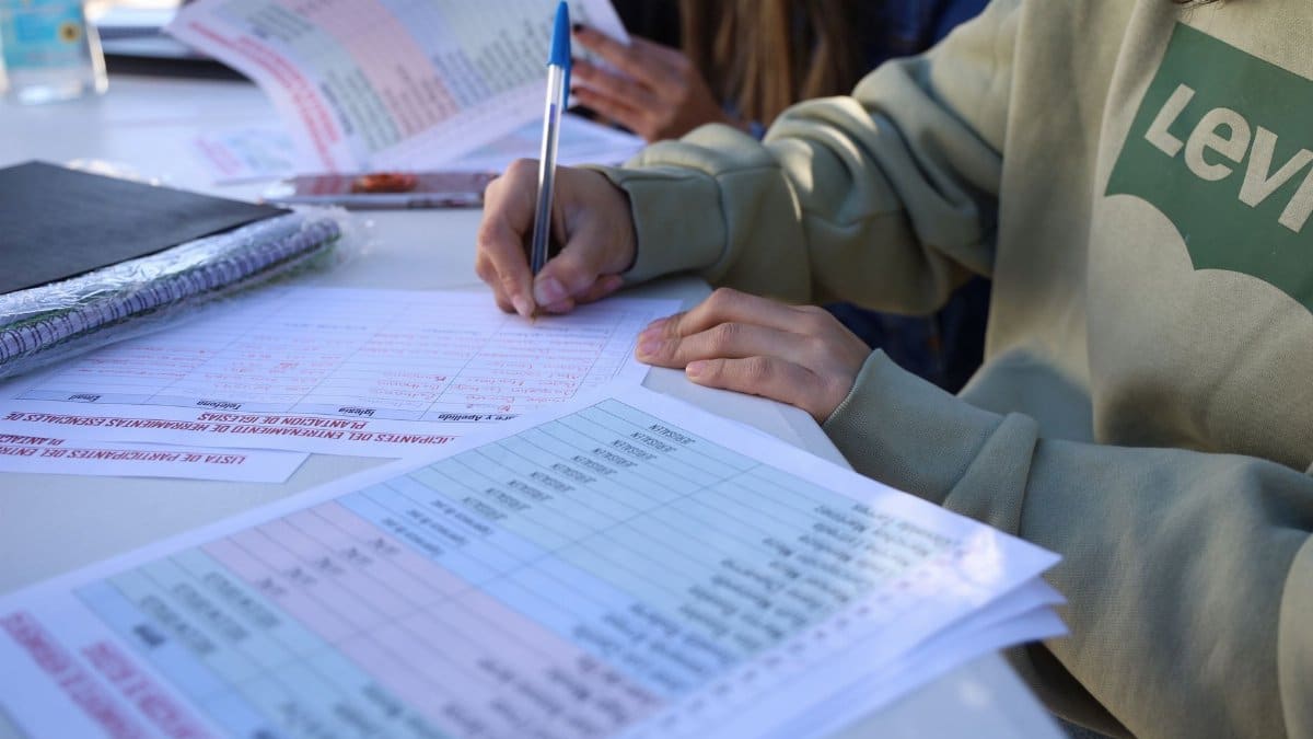 Person writing on documents outdoors, focusing on planning and organization.