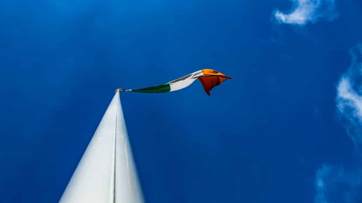 Low-angle view of the Irish flag waving against a vibrant blue sky in Dublin.