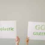 Hands holding eco-friendly signs advocating 'No Plastic' and 'Go Green'. Environmental awareness concept.