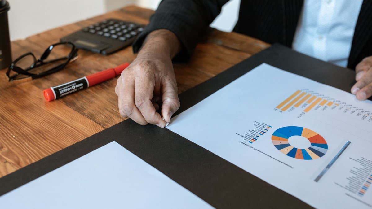 Close-up of a business setting with charts, documents, and a hand pointing.