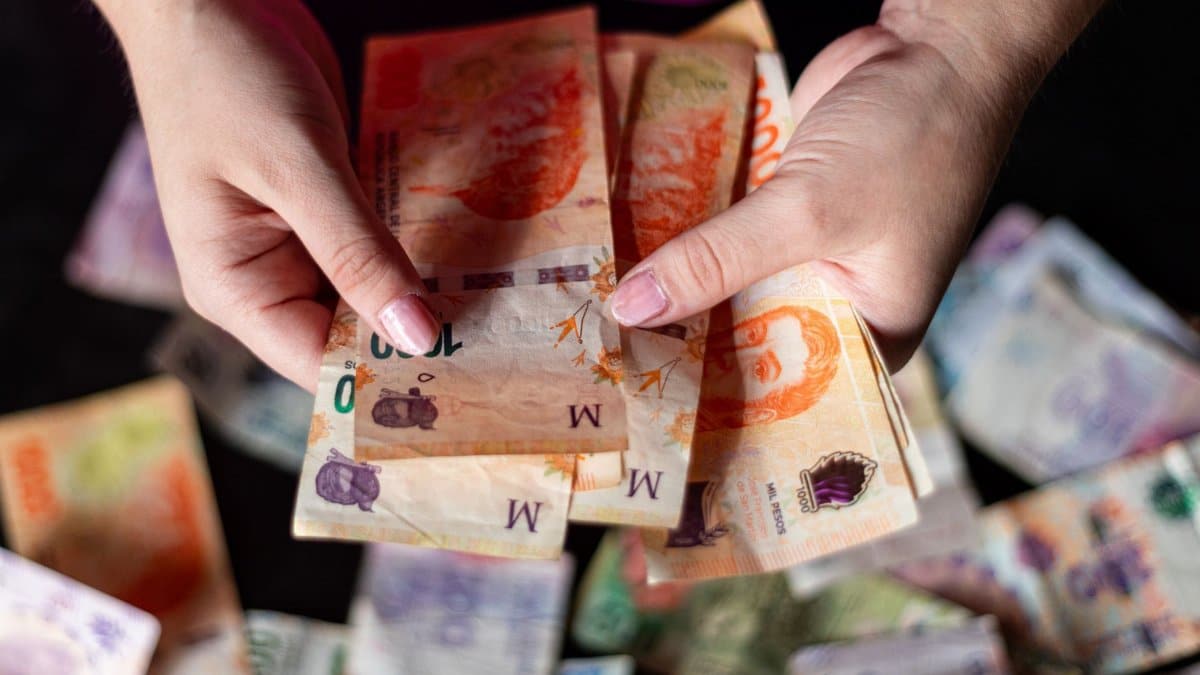 Hands holding Argentine peso notes, representing currency and finance in Buenos Aires, Argentina.
