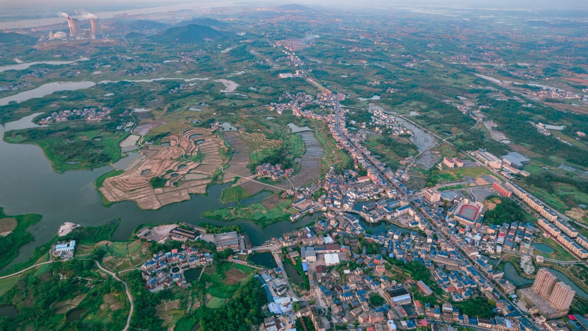 Aerial photograph showcasing Jiujiang's industrial and scenic suburban areas with roads and residential buildings.