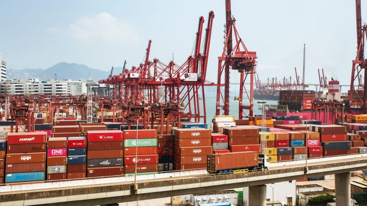 A bustling scene of cargo containers and cranes at a Hong Kong port, showcasing global trade.