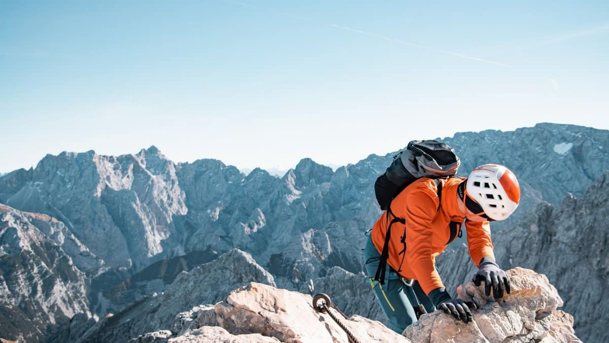 Adventurous climber scaling a rocky peak in Krün, Bavaria with a vast mountain backdrop.