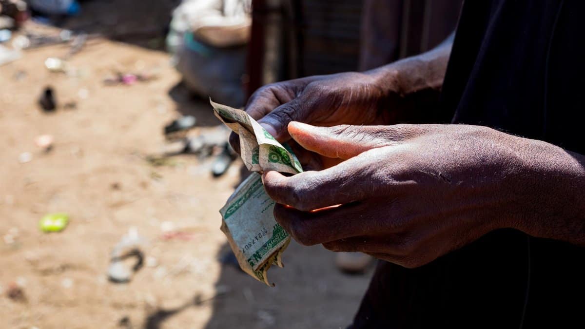 Detailed view of hands counting Nigerian naira outdoors, signifying economic activity.