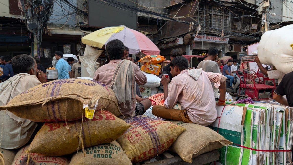 Street vendors and laborers taking a break amidst the bustling city life of Delhi, India.