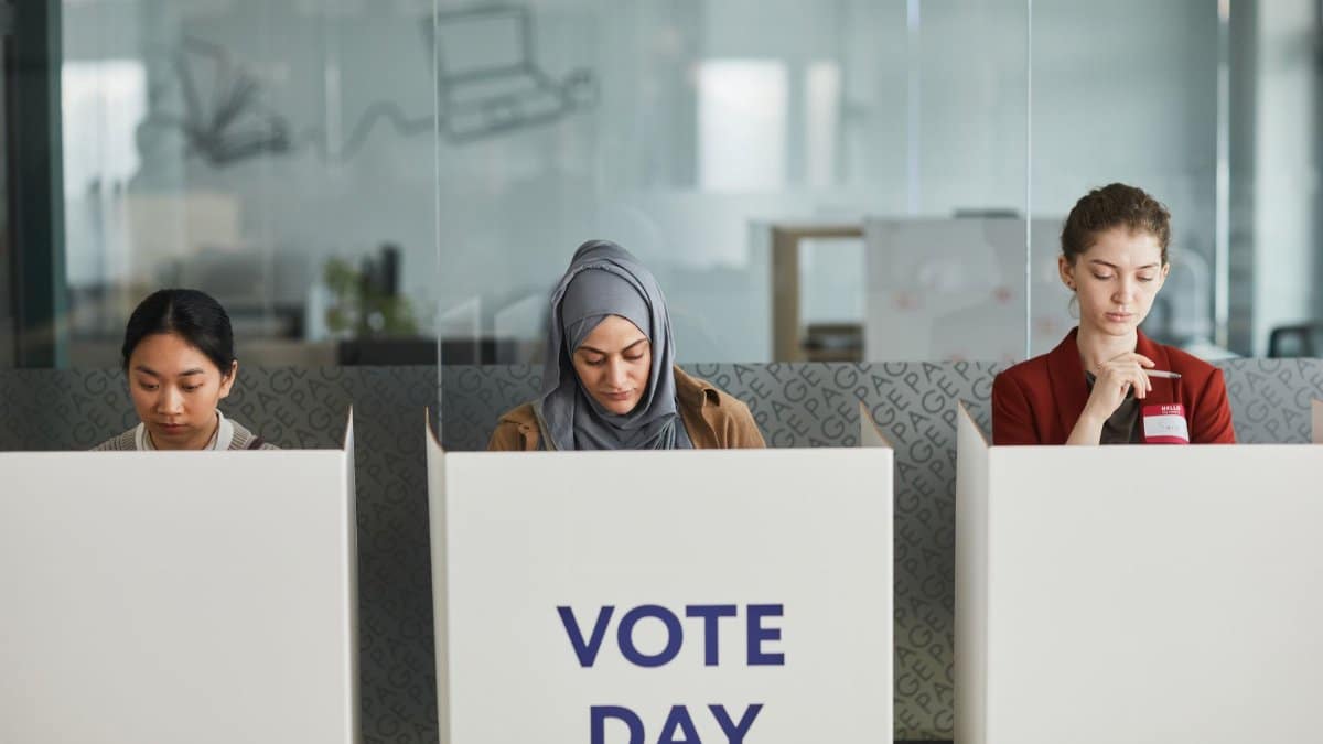 Three women voting in office cubicles. Diverse representation, focused and serious.