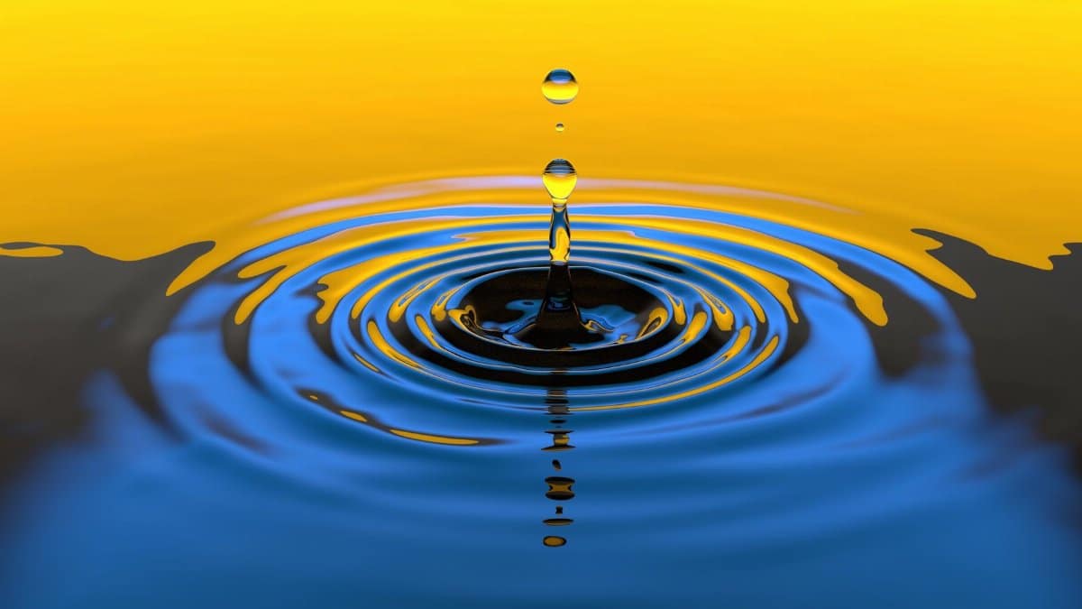 Close-up macro shot of a water droplet creating ripples with vibrant colors.