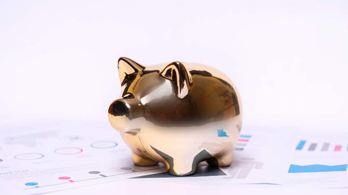 Close-up of a golden piggy bank on financial documents, symbolizing savings and investment.