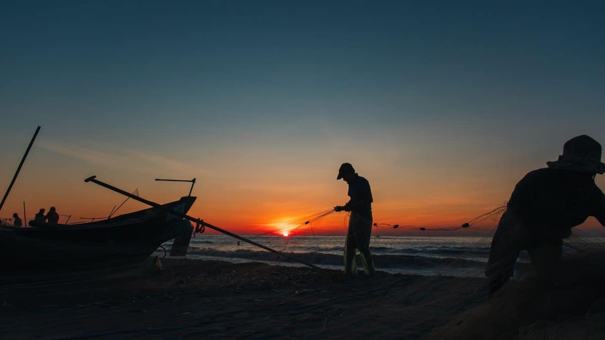 Silhouetted fishermen haul in nets at sunrise on Quang Tri beach, Vietnam, capturing the serene beauty of a coastal morning.