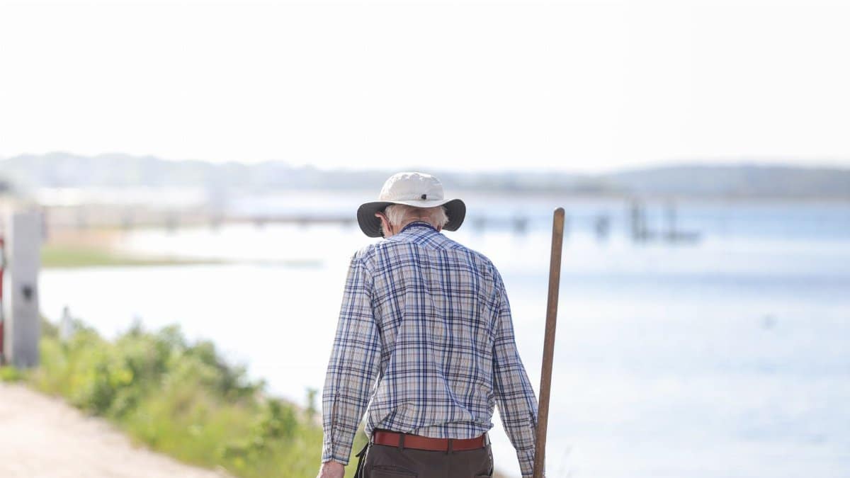 Senior man strolls by the water in Bourne, Massachusetts on a sunny day.
