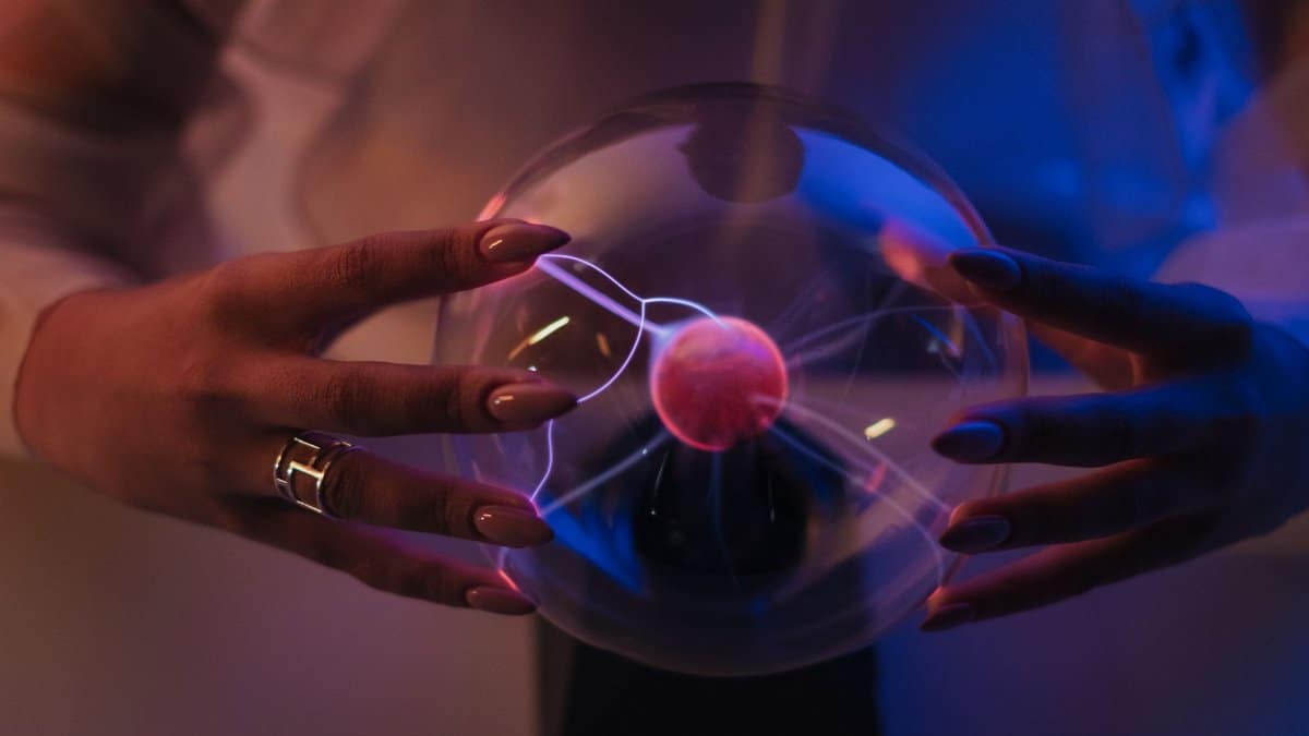 A woman elegantly holds a glowing plasma globe, creating stunning visual effects.
