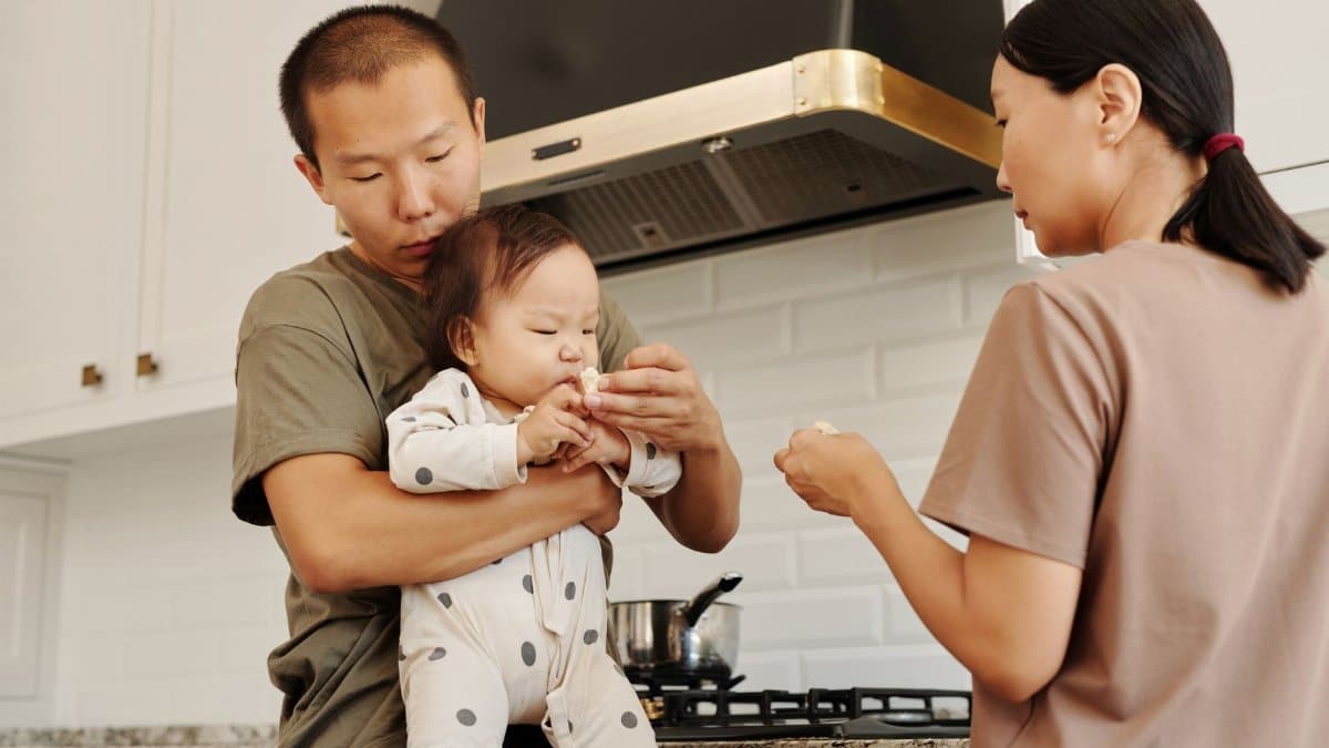 Family feeding time in a cozy kitchen as parents care for their baby.