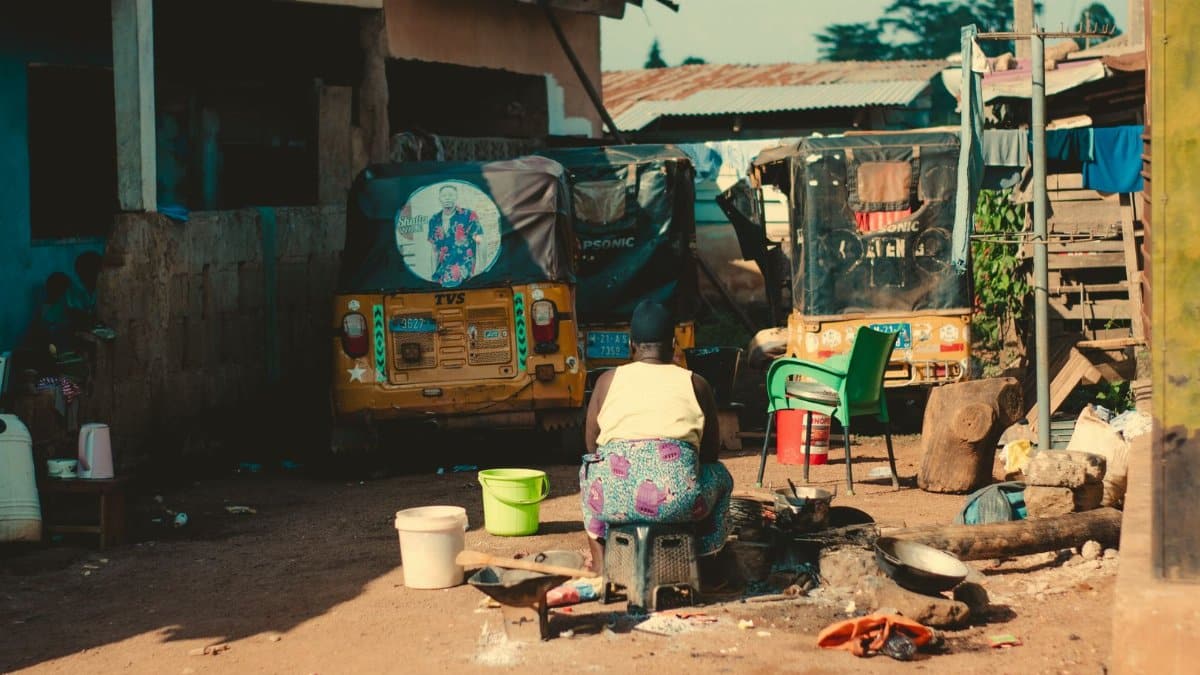 Outdoor scene of daily village life in Africa with rickshaws and street cooking.