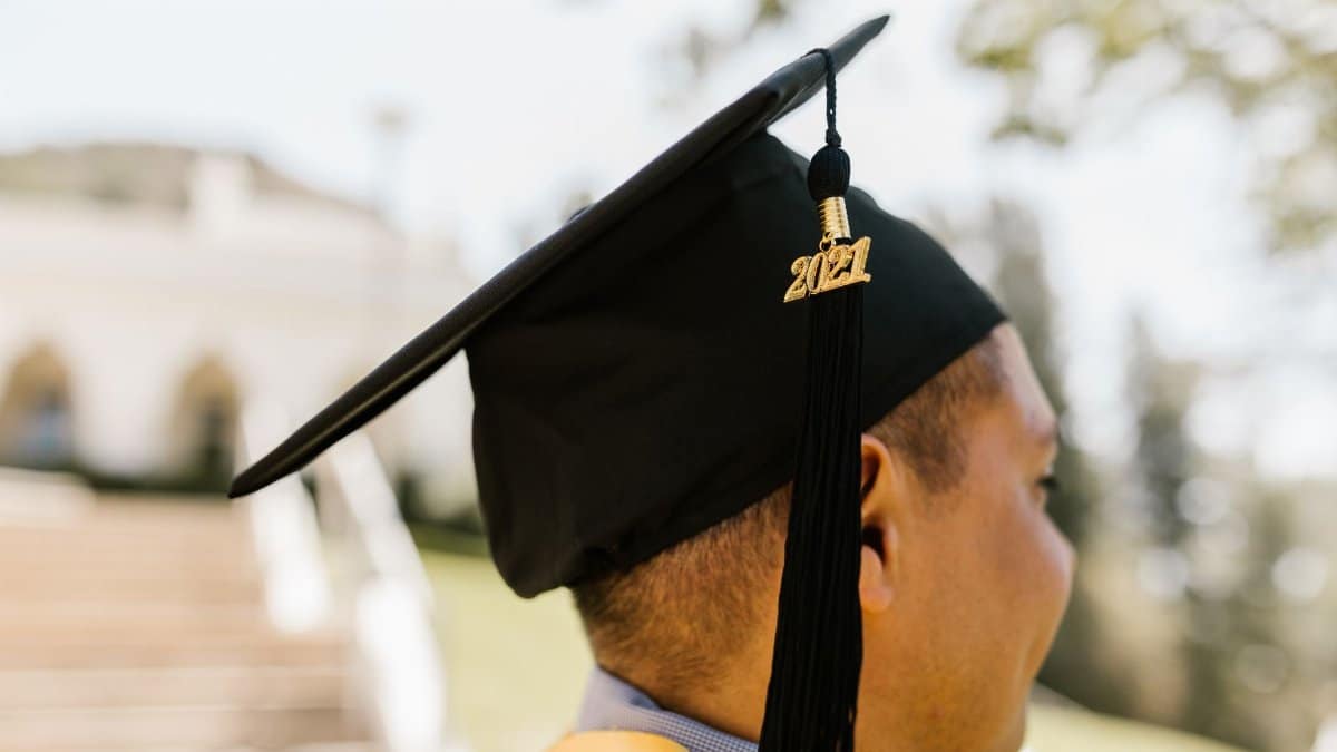 Graduate wearing mortarboard celebrates achievement on sunny day