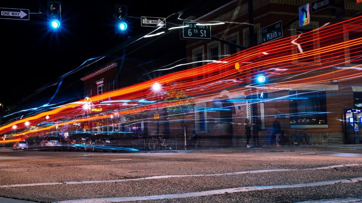 Long exposure photo capturing vibrant light trails on a downtown street at night.