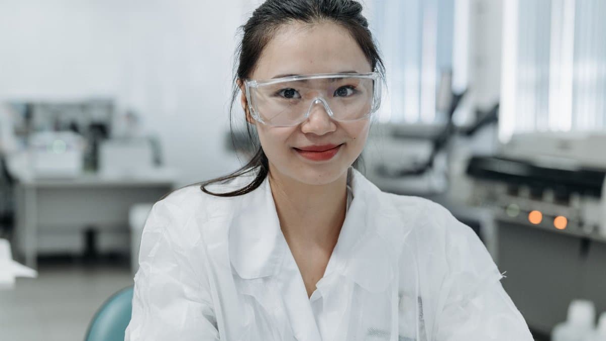 Smiling female scientist wearing safety goggles in a modern laboratory.