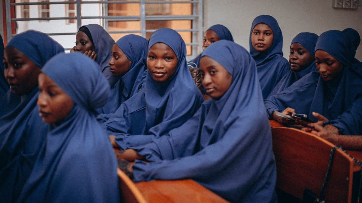 Group of young students in blue hijabs attending class, reflecting focus and education.