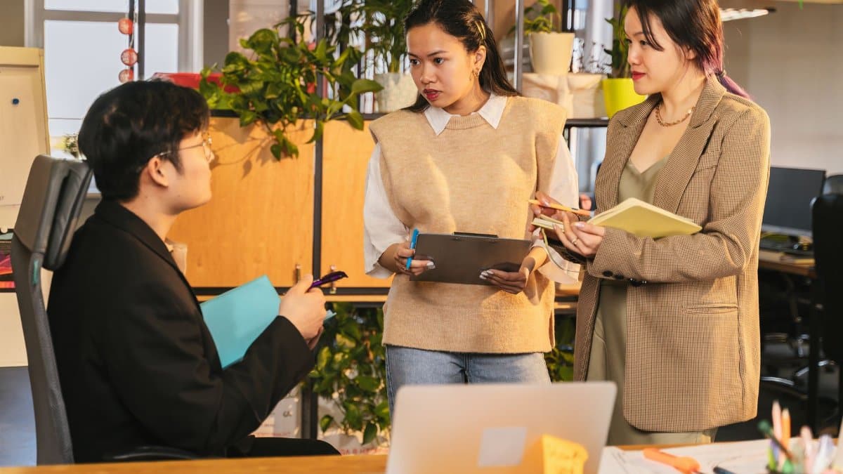 Three colleagues engaging in a discussion at a contemporary office setting.