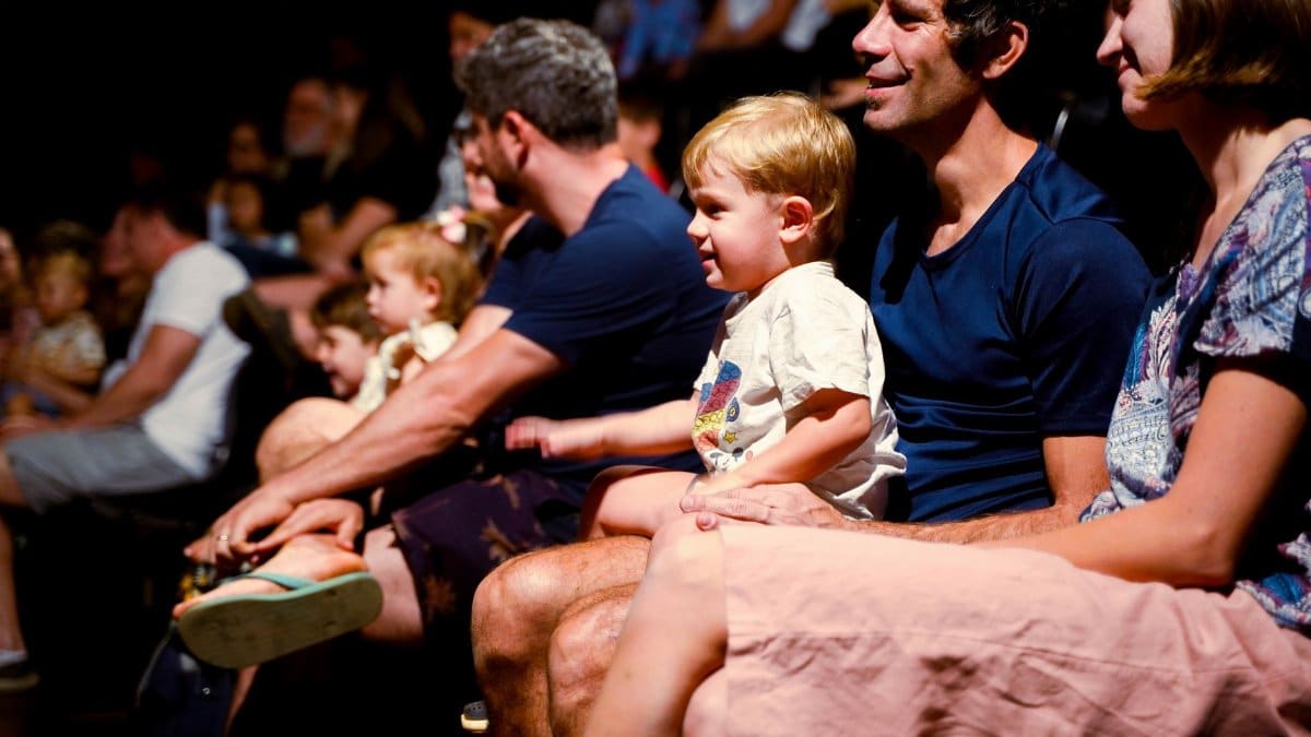 A diverse audience, including families, enjoys a live performance in a Brasil theater.