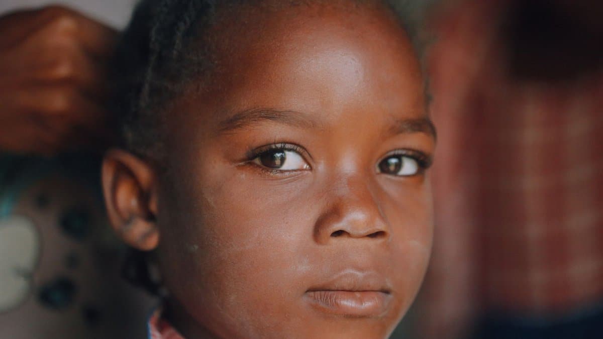 Close-up portrait of a young Haitian girl with expressive eyes and calm demeanor.