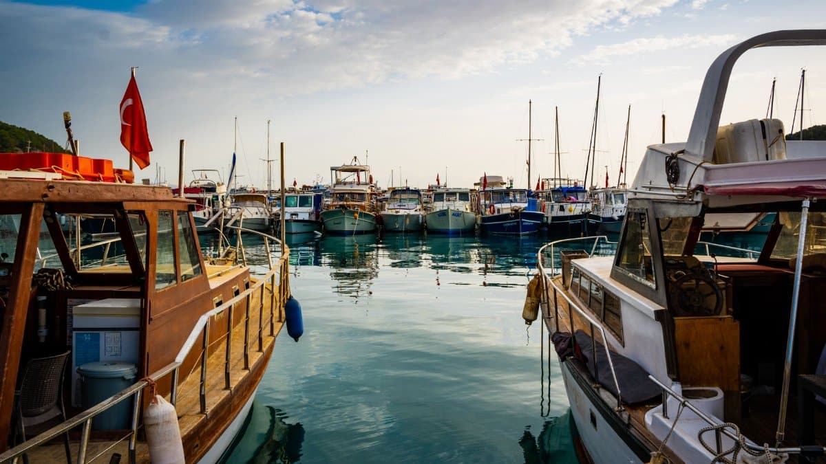 A scenic view of boats docked at a harbor under a cloudy sky in Turkey.